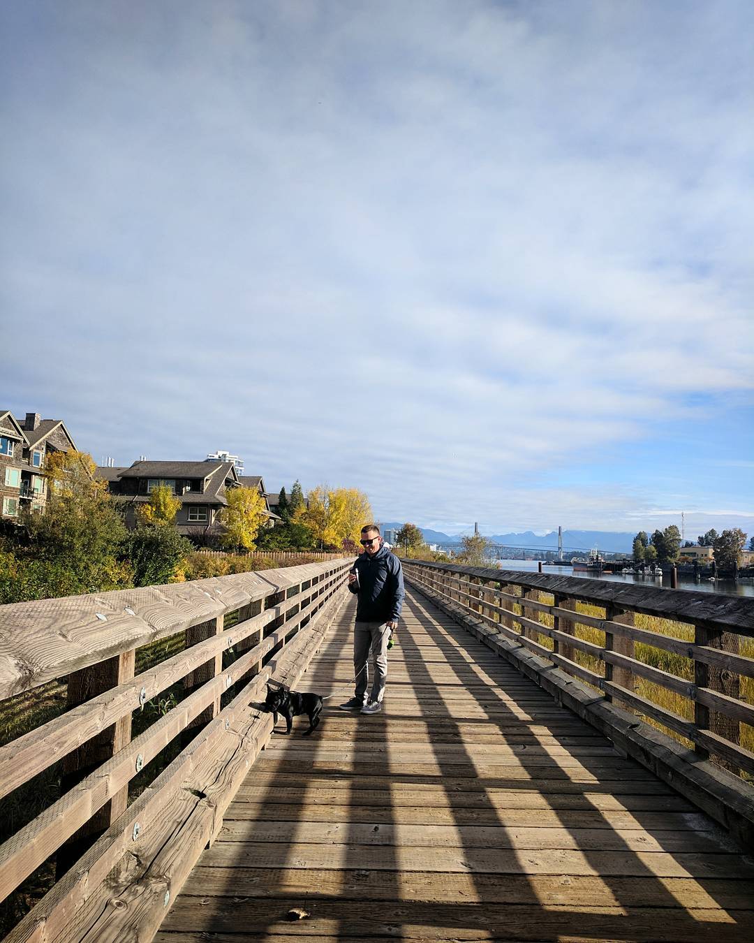 Man and dog on wooden bridge near river